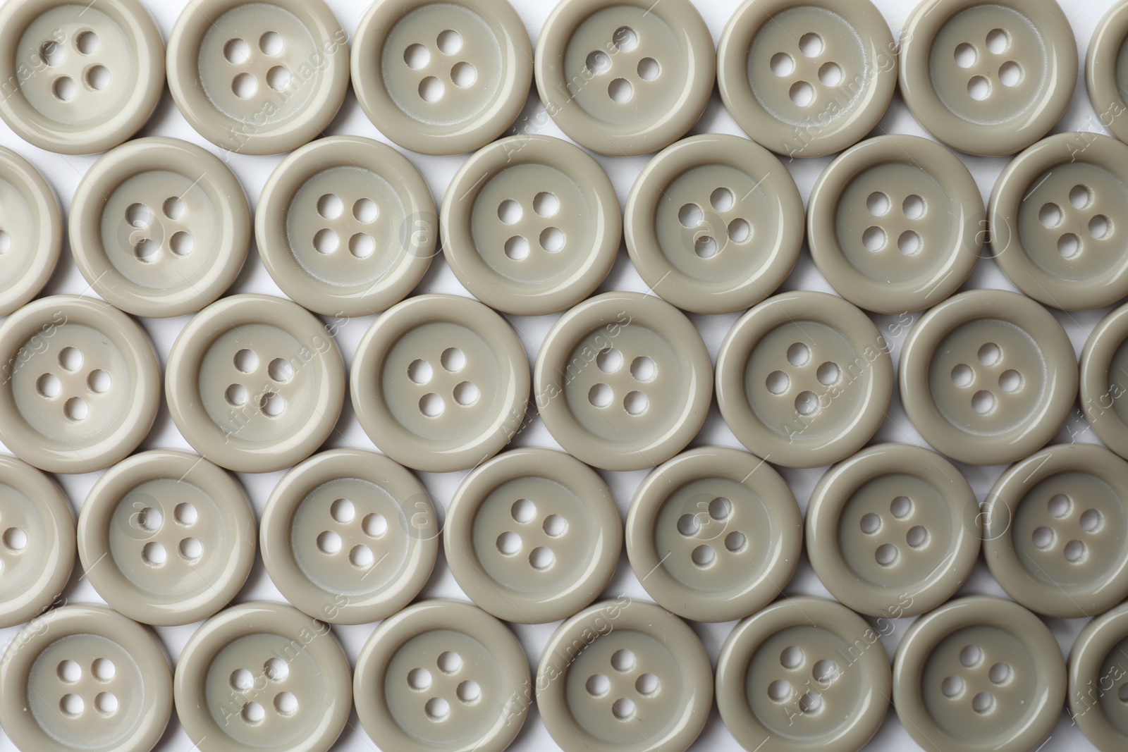 Photo of Many grey sewing buttons on white background, closeup