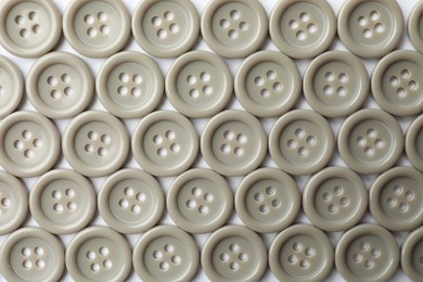 Photo of Many grey sewing buttons on white background, closeup