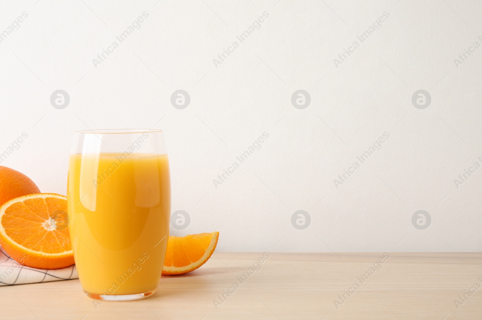 Photo of Glass of orange juice and fresh fruits on wooden table. Space for text