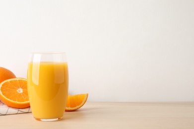 Photo of Glass of orange juice and fresh fruits on wooden table. Space for text