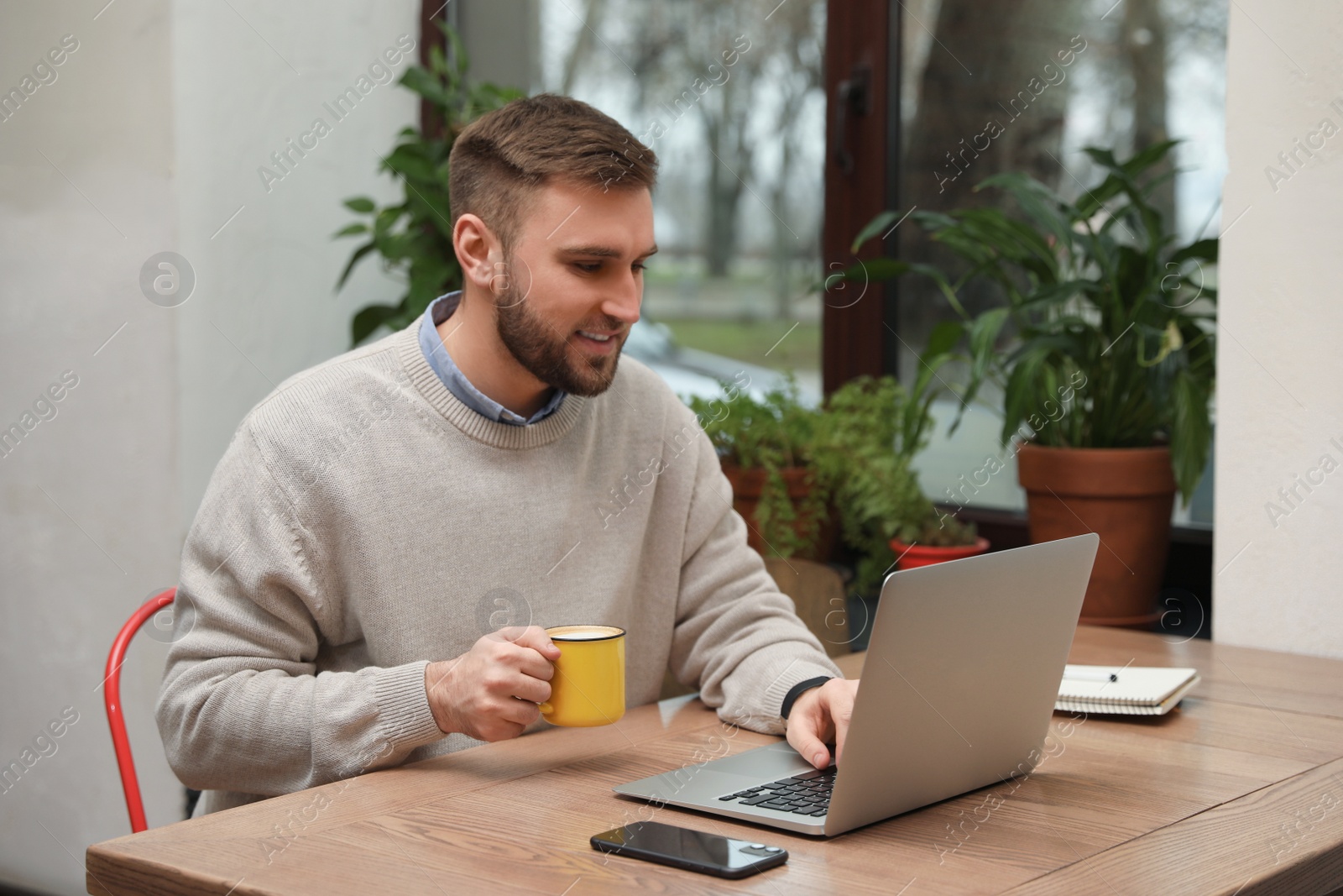 Photo of Male blogger working with laptop at table in cafe