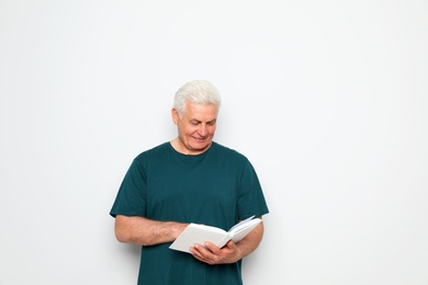Photo of Senior man reading book on white background, space for text
