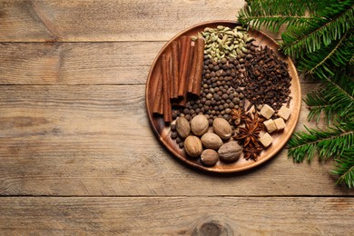 Photo of Different spices, nuts and fir branches on wooden table, flat lay. Space for text