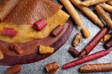 Delicious fruit leather rolls on grey table, flat lay