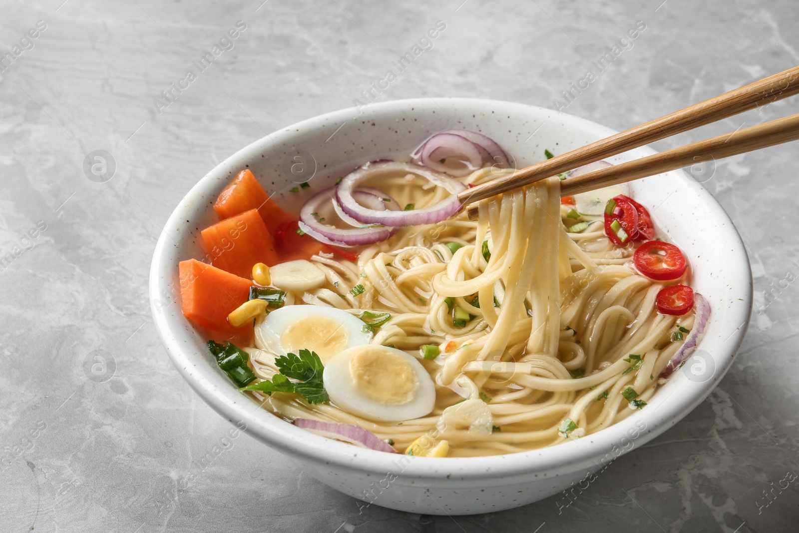 Photo of Eating noodle dish with chopsticks on table, closeup