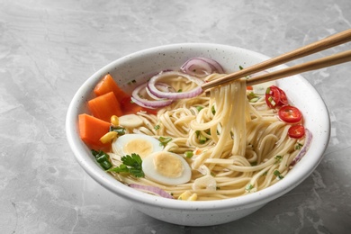 Eating noodle dish with chopsticks on table, closeup