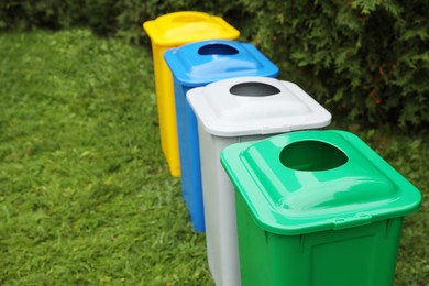 Photo of Many color recycling bins on green grass outdoors, space for text