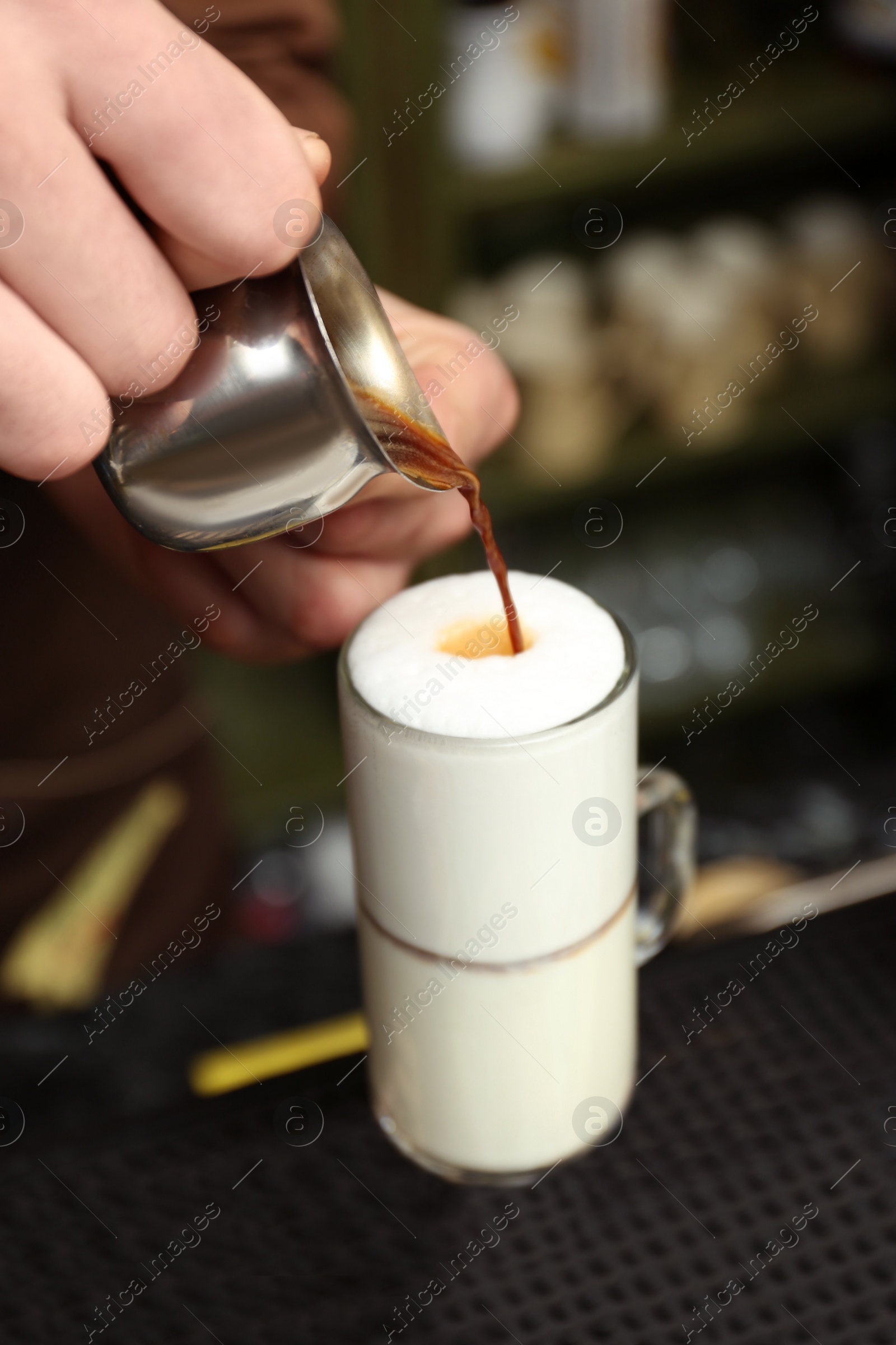 Photo of Barista adding coffee to steamed milk at counter, closeup view