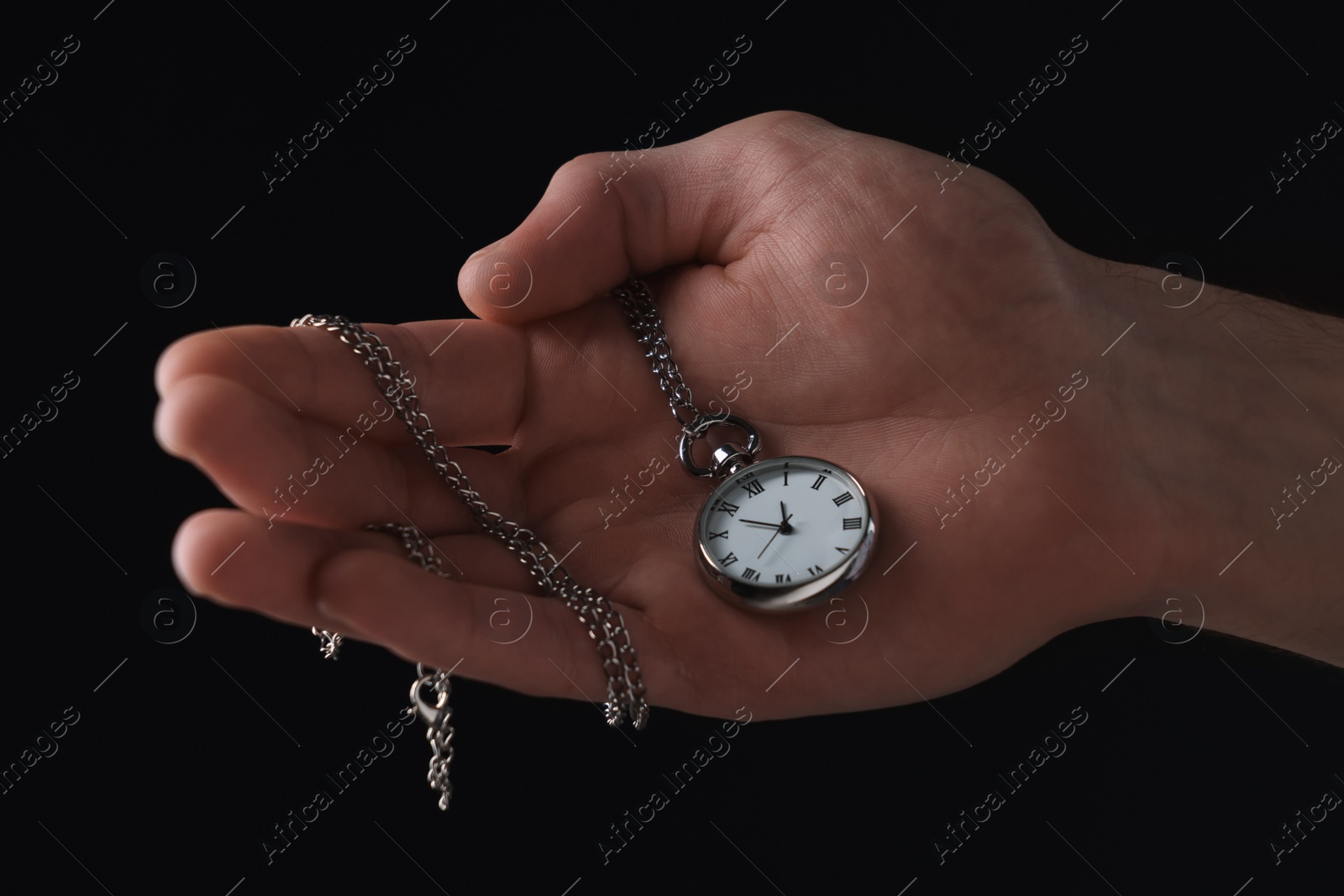 Photo of Man holding chain with elegant pocket watch on black background, closeup