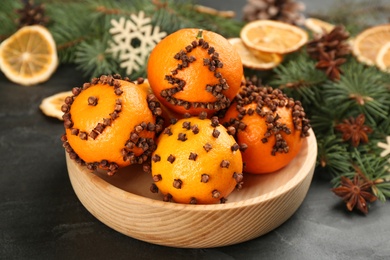 Photo of Pomander balls made of fresh tangerines with cloves  on dark table, closeup. Christmas atmosphere