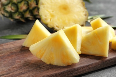 Photo of Wooden board with fresh sliced pineapple, closeup