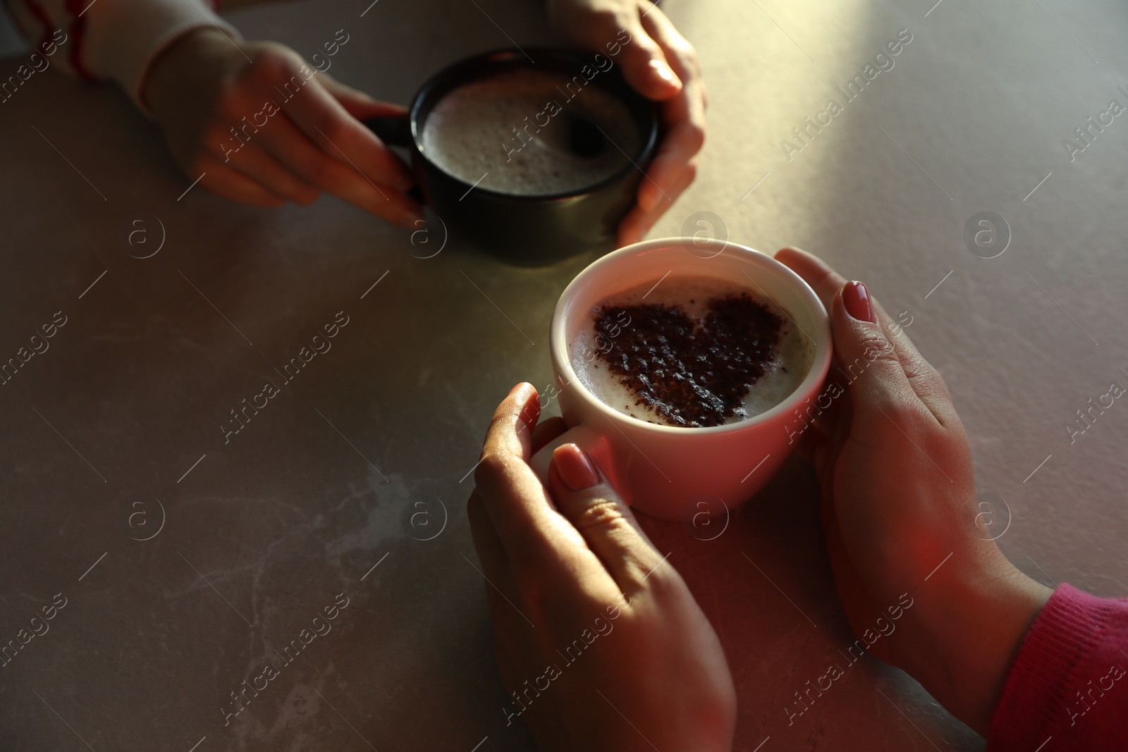 Photo of Women with cups of hot coffee at grey table, closeup