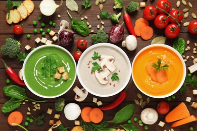 Various cream soups and ingredients on wooden background, flat lay. Healthy food