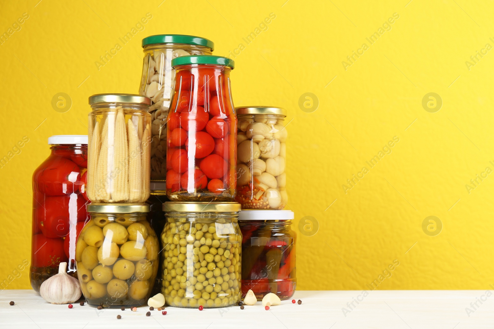 Photo of Jars of pickled vegetables on white wooden table. Space for text