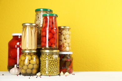 Jars of pickled vegetables on white wooden table. Space for text