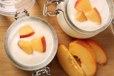Photo of Delicious yogurt with fresh peach on wooden table, flat lay