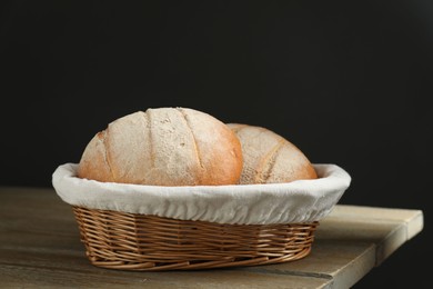 Photo of Wicker basket with fresh bread on wooden table