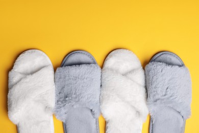 Photo of Different soft fluffy slippers on yellow background, flat lay. Space for text