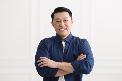 Portrait of smiling businessman near white wall indoors