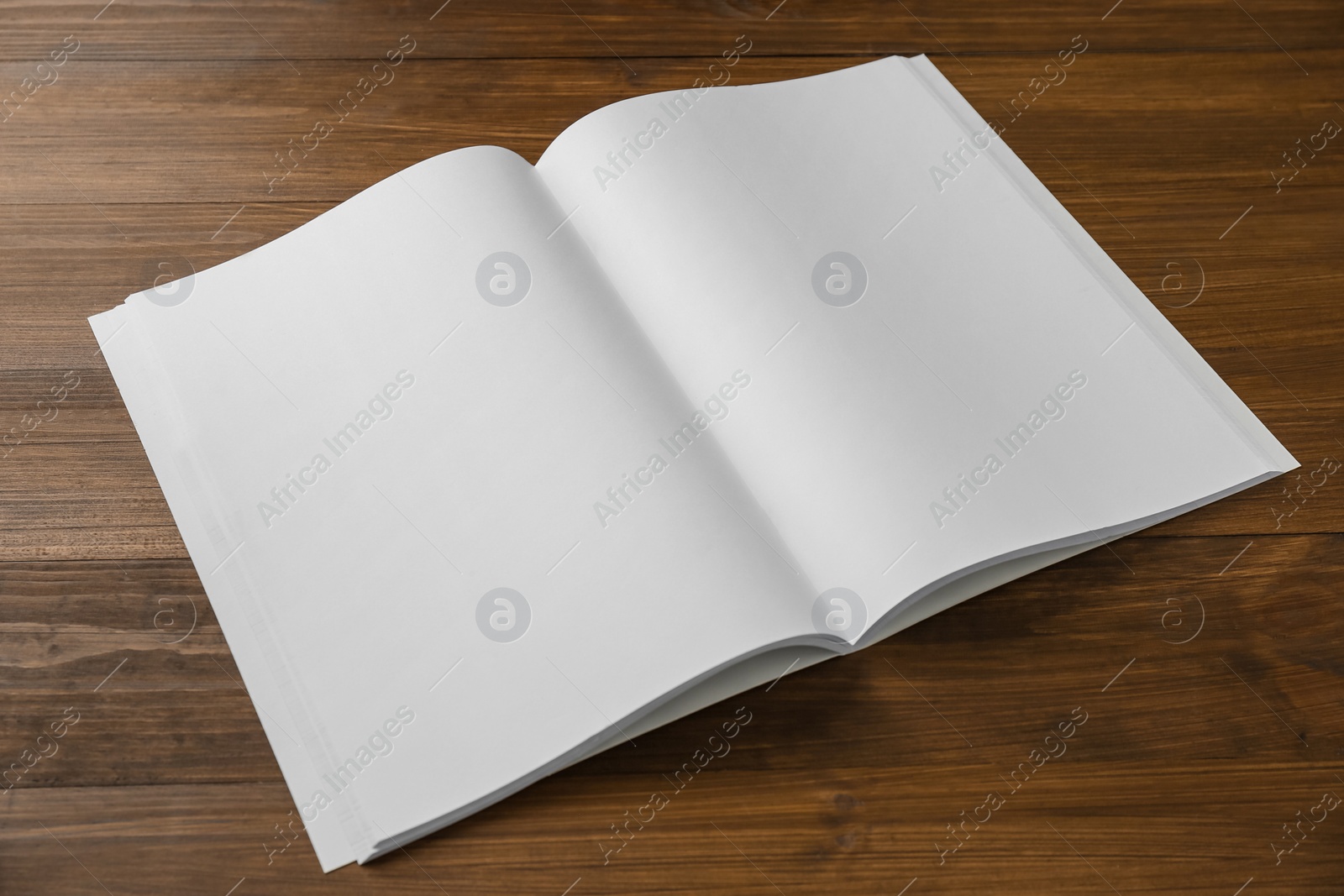 Photo of Open blank paper brochure on wooden table. Mockup for design