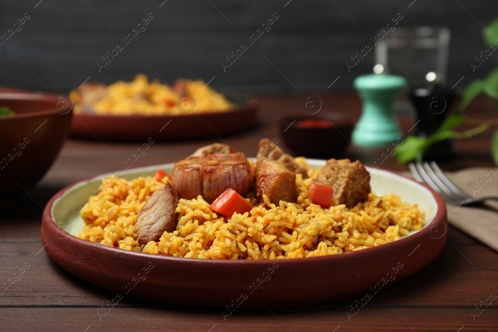 Photo of Plate with rice pilaf and meat on wooden table