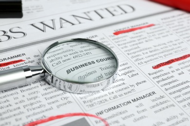 Photo of Magnifying glass and marker on newspaper. Job search concept