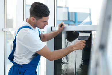 Professional worker tinting window with foil indoors