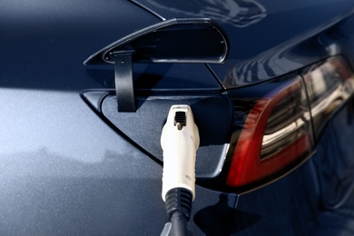 Photo of Charging modern electric car from station, closeup