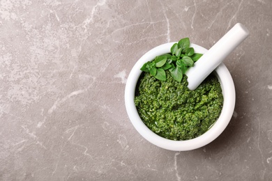 Mortar with homemade basil pesto sauce and pestle on table, top view. Space for text