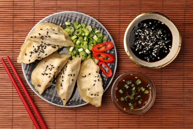 Photo of Delicious gyoza (asian dumplings) served on bamboo mat, flat lay