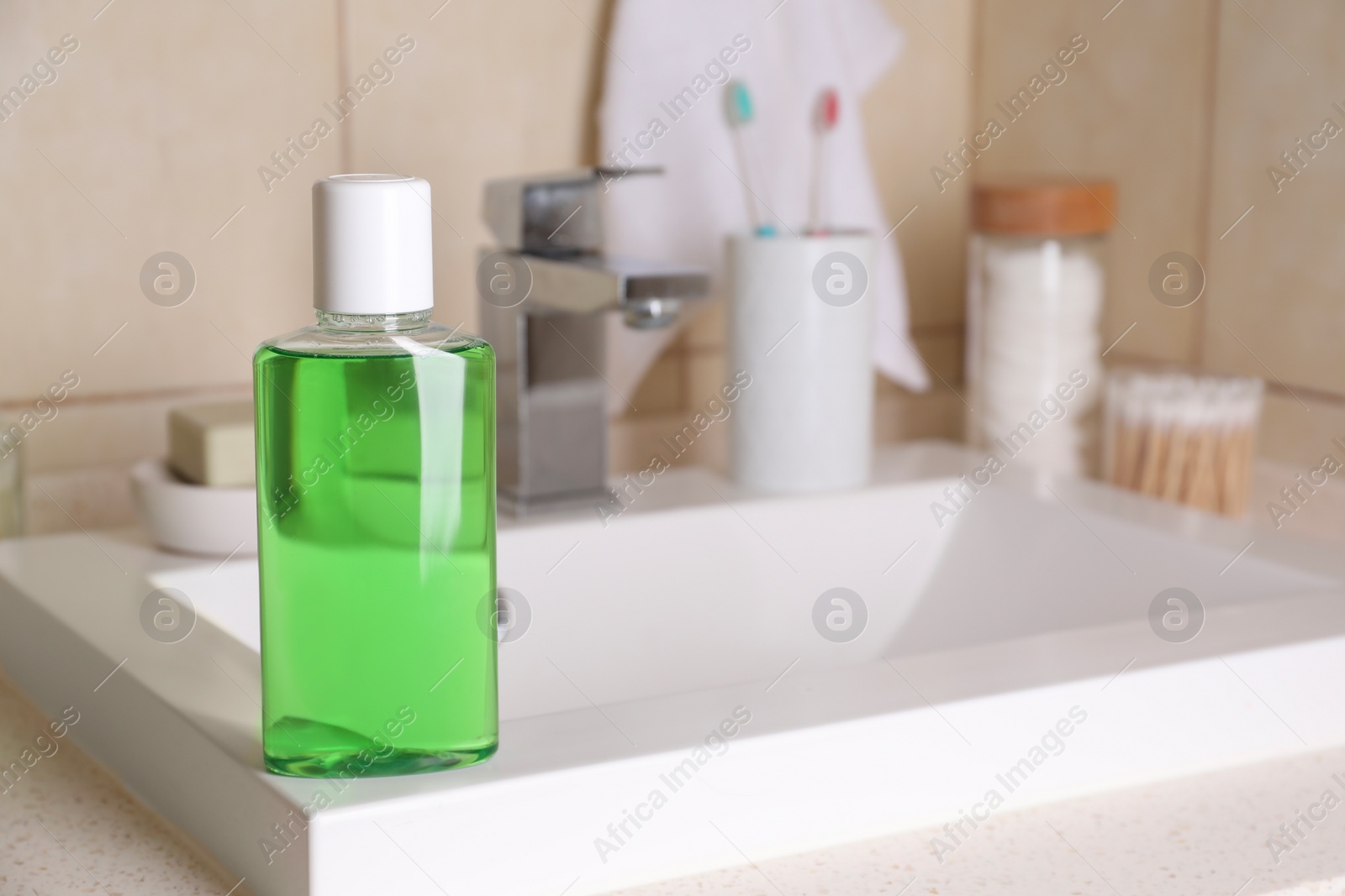 Photo of Fresh mouthwash in bottle on sink in bathroom. Space for text