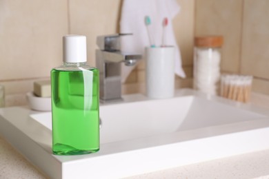 Fresh mouthwash in bottle on sink in bathroom. Space for text