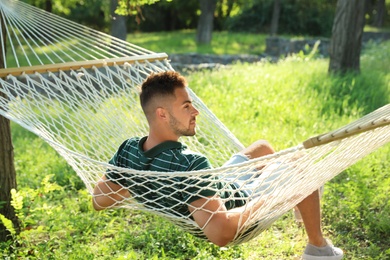 Young man resting in comfortable hammock at green garden