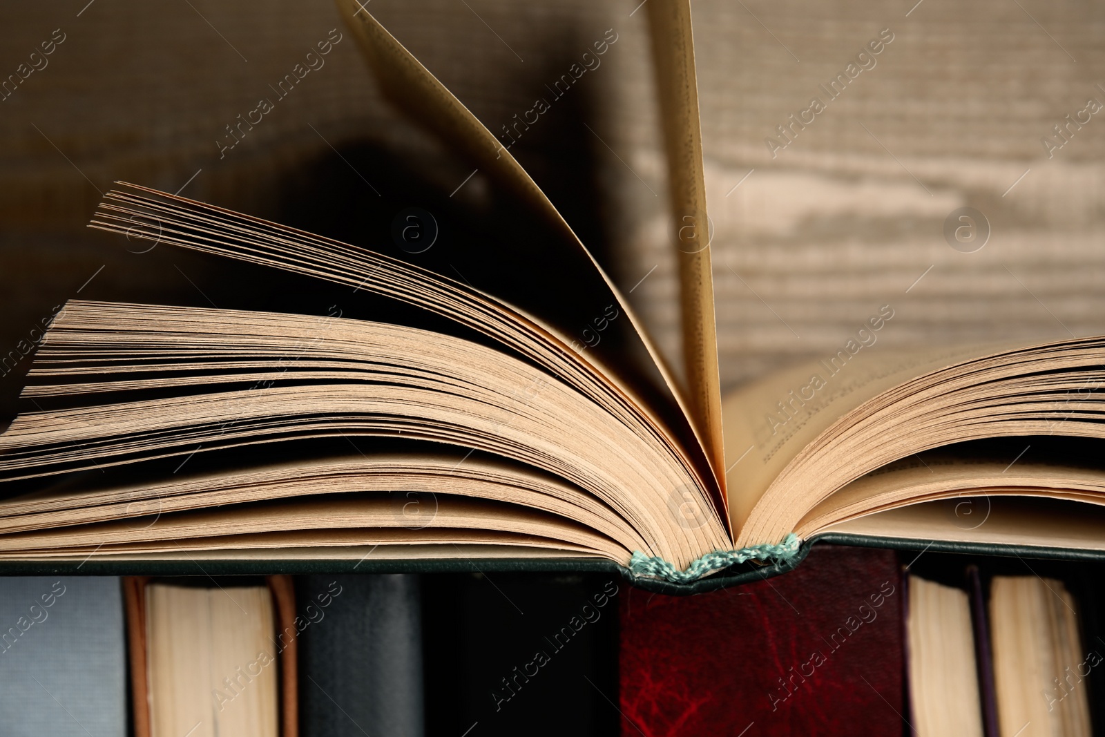 Photo of Open hardcover book near wooden background, closeup