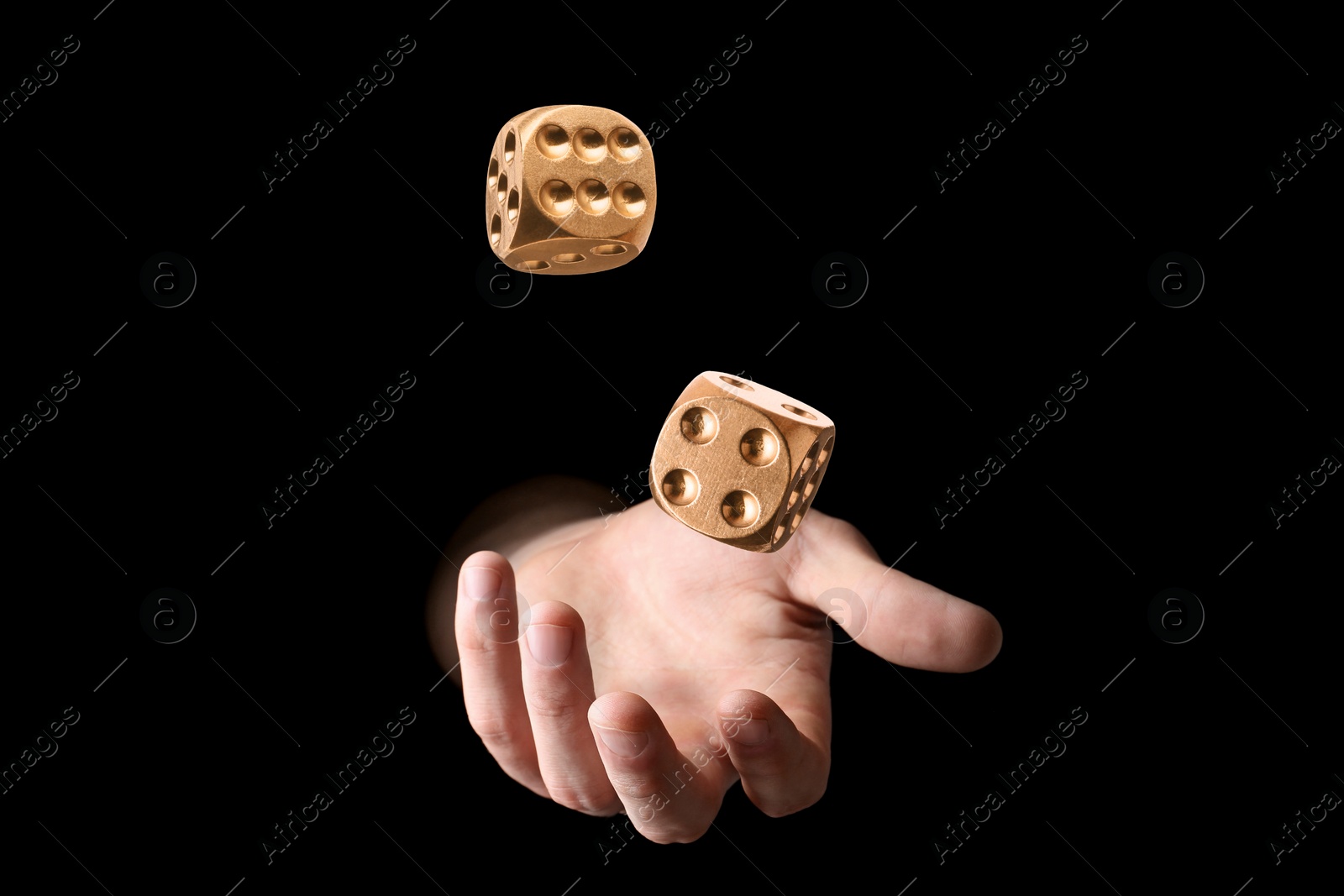 Image of Man throwing golden dice on black background, closeup