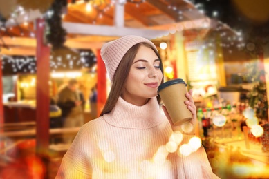 Image of Happy beautiful woman with paper cup of mulled wine at Christmas fair