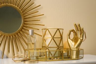 Photo of Composition with golden accessories and jewelry on dressing table near color wall