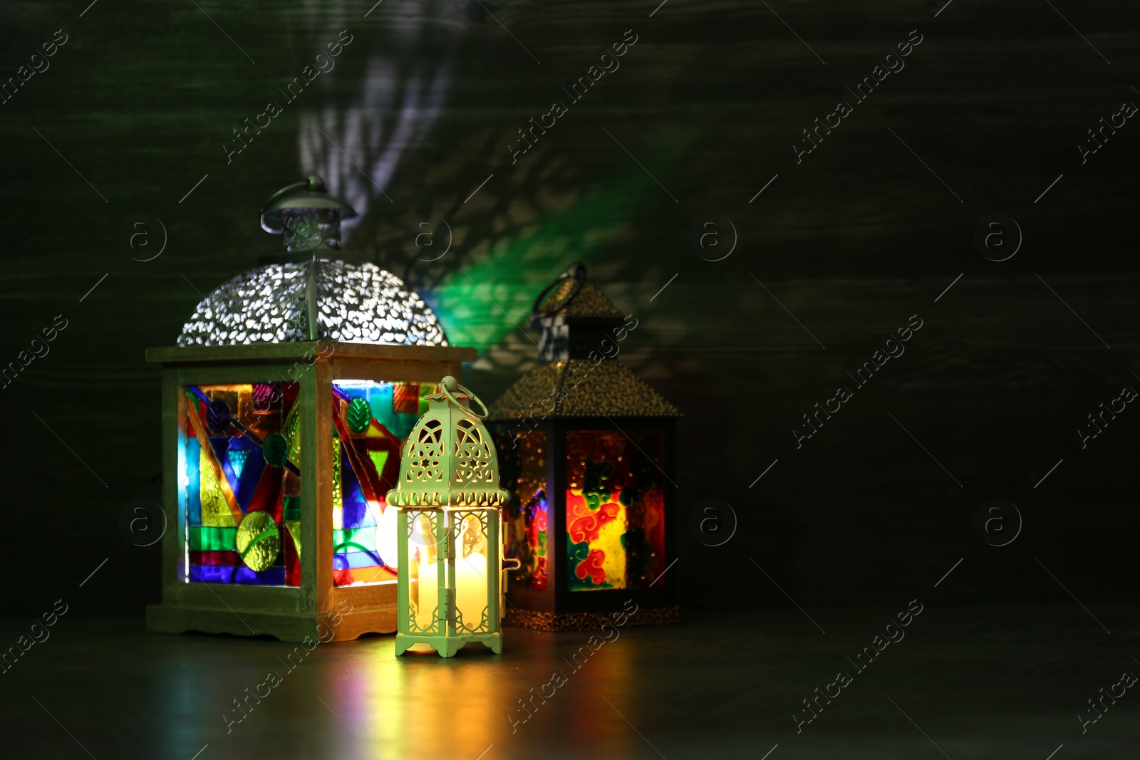 Photo of Decorative Arabic lanterns on table against dark background. Space for text