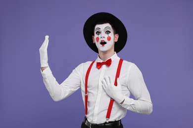 Photo of Mime artist making excited face on purple background