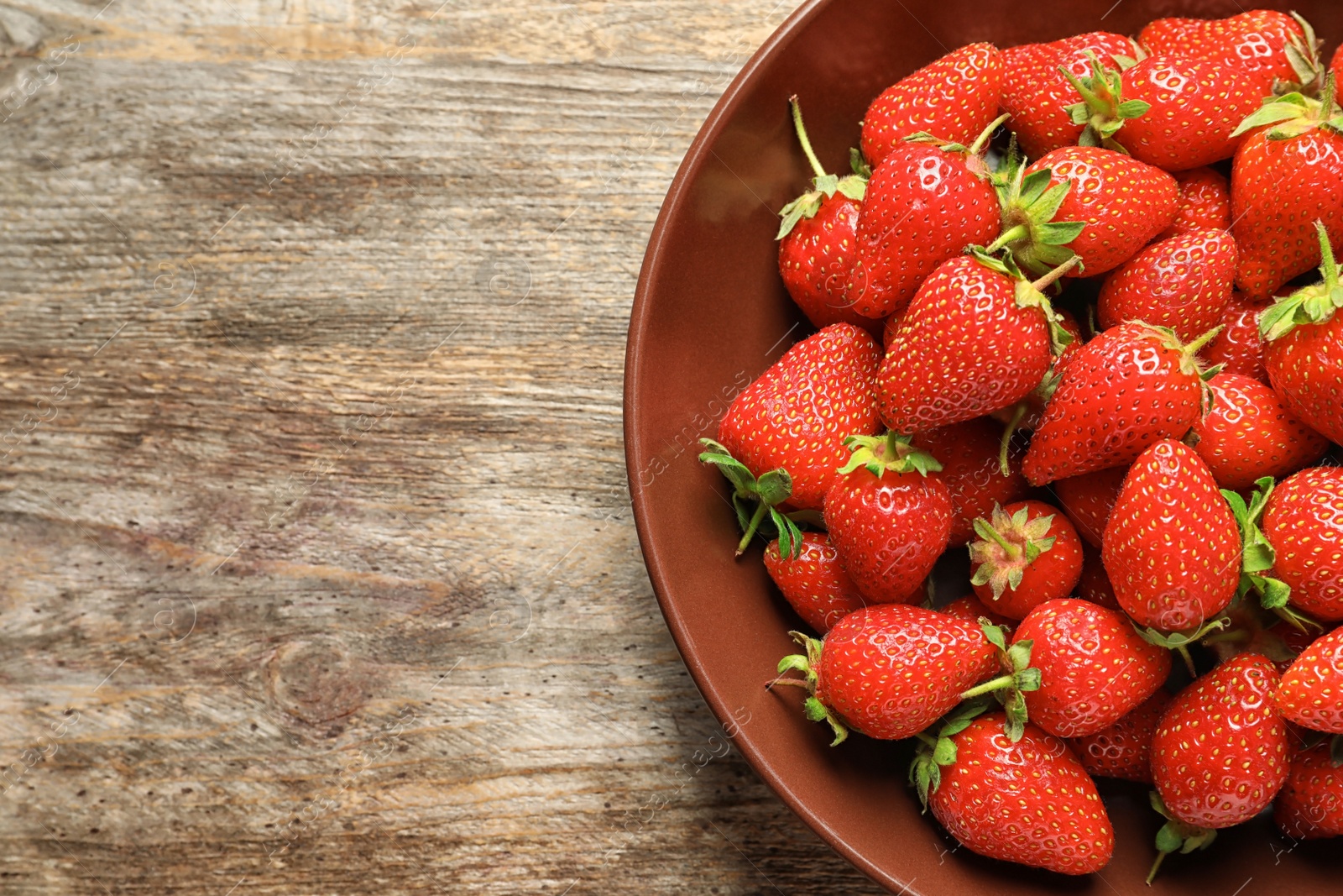 Photo of Plate with fresh ripe strawberries on wooden background, top view