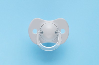 One new baby pacifier on light blue background, top view