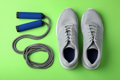 Photo of Jump rope and sneakers on color background. Healthy lifestyle