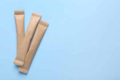 Photo of Beige sticks of sugar on light blue background, flat lay. Space for text