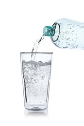 Pouring soda water from bottle into glass on white background