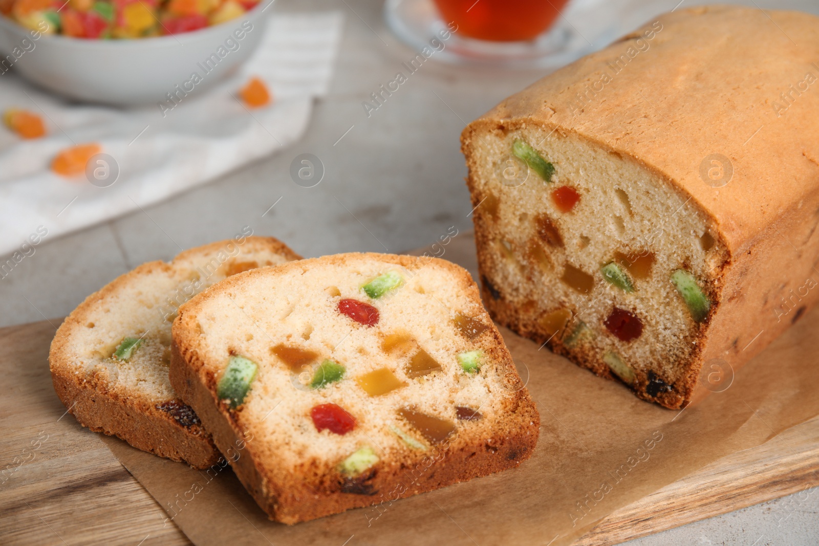 Photo of Delicious cake with candied fruits on wooden board, closeup