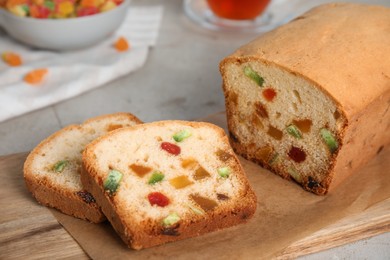 Photo of Delicious cake with candied fruits on wooden board, closeup