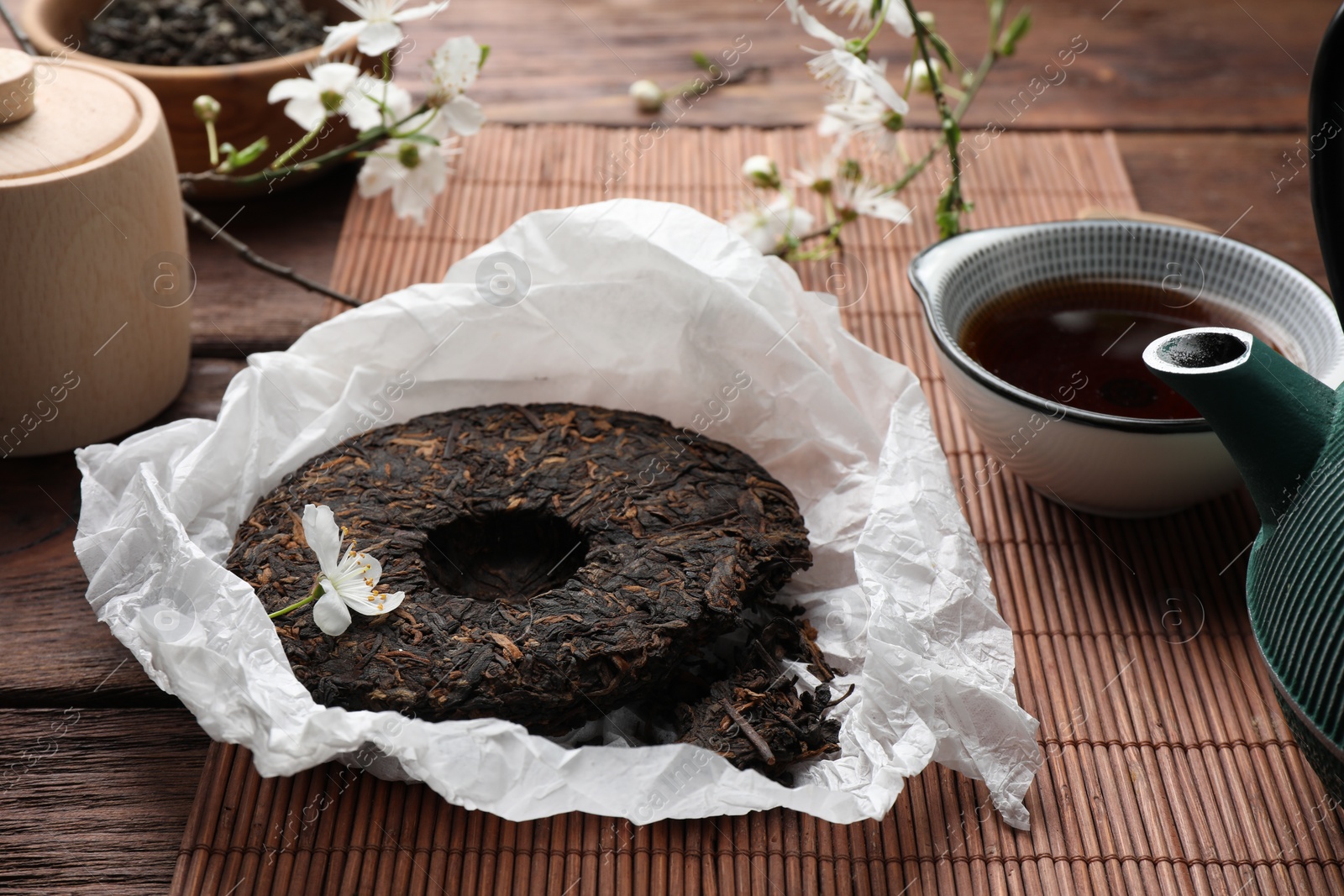 Photo of Broken disc shaped pu-erh tea and cup with drink on wooden table