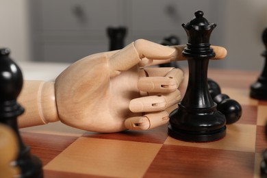 Photo of Robot moving chess piece on board, closeup. Wooden hand representing artificial intelligence