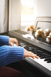 Young woman playing piano at home, closeup