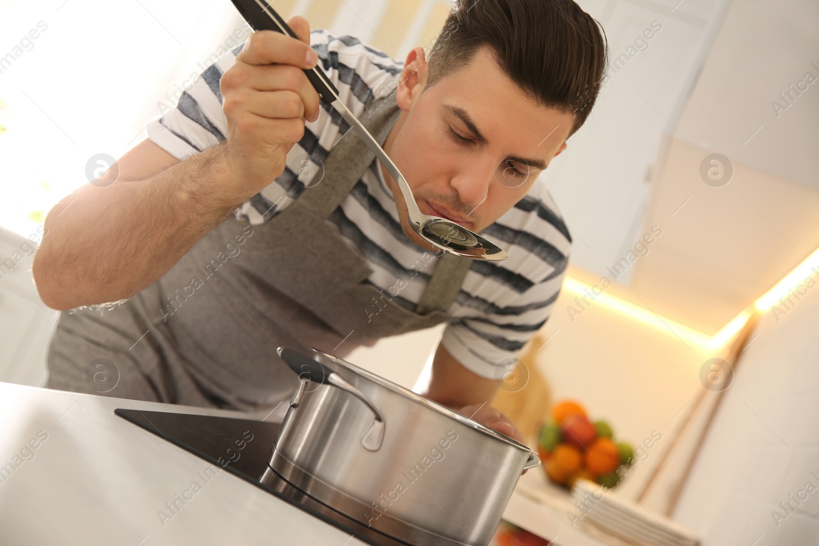 Photo of Handsome man cooking on stove in kitchen